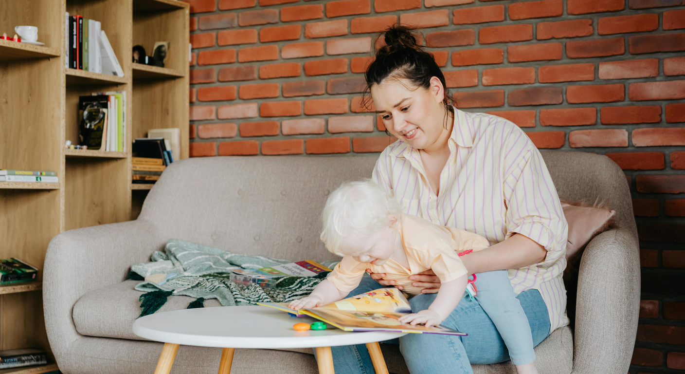 Mother and toddler comparing bilingual learning books at a sunlit kitchen table