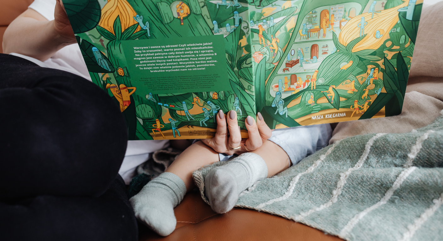 Wooden table with an open bilingual activity book and Montessori cards in warm daylight