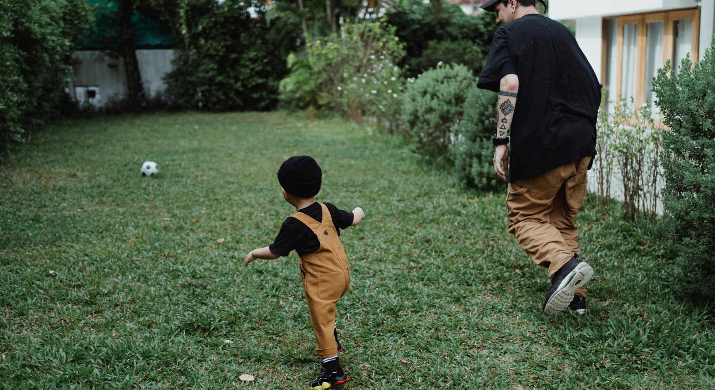 A parent and toddler playing together in a sunny backyard.
