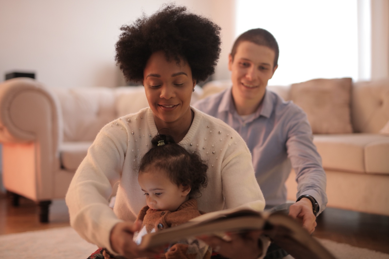 A warm family reading a picture book together at home in soft light.