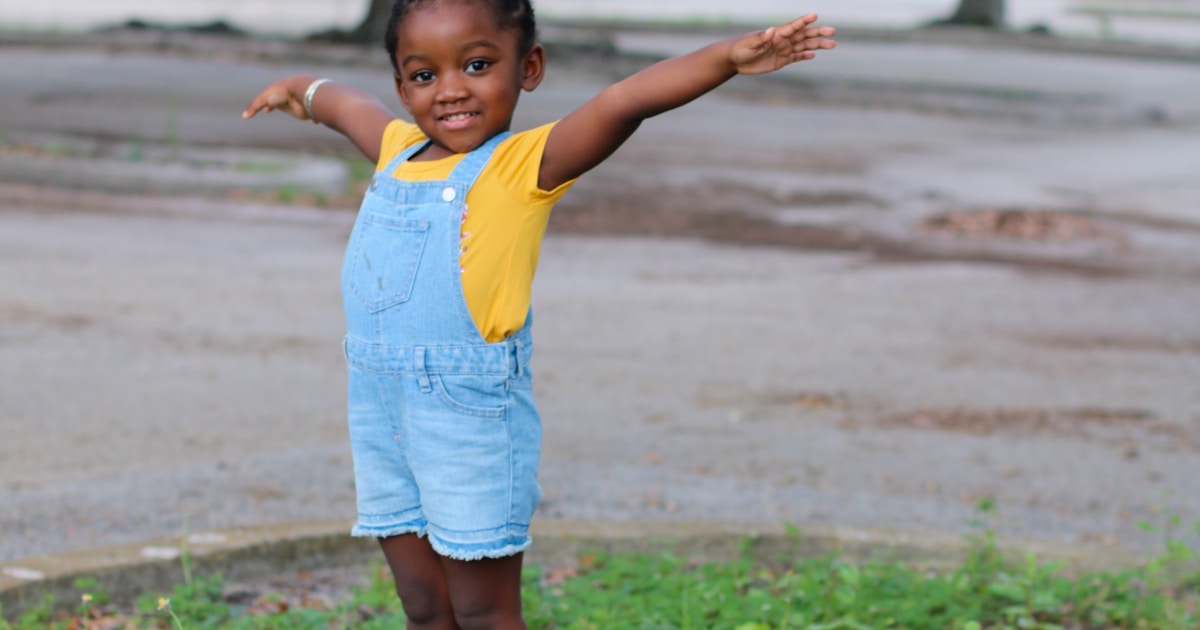 girl in yellow shirt standing on gray concrete blocks during daytime